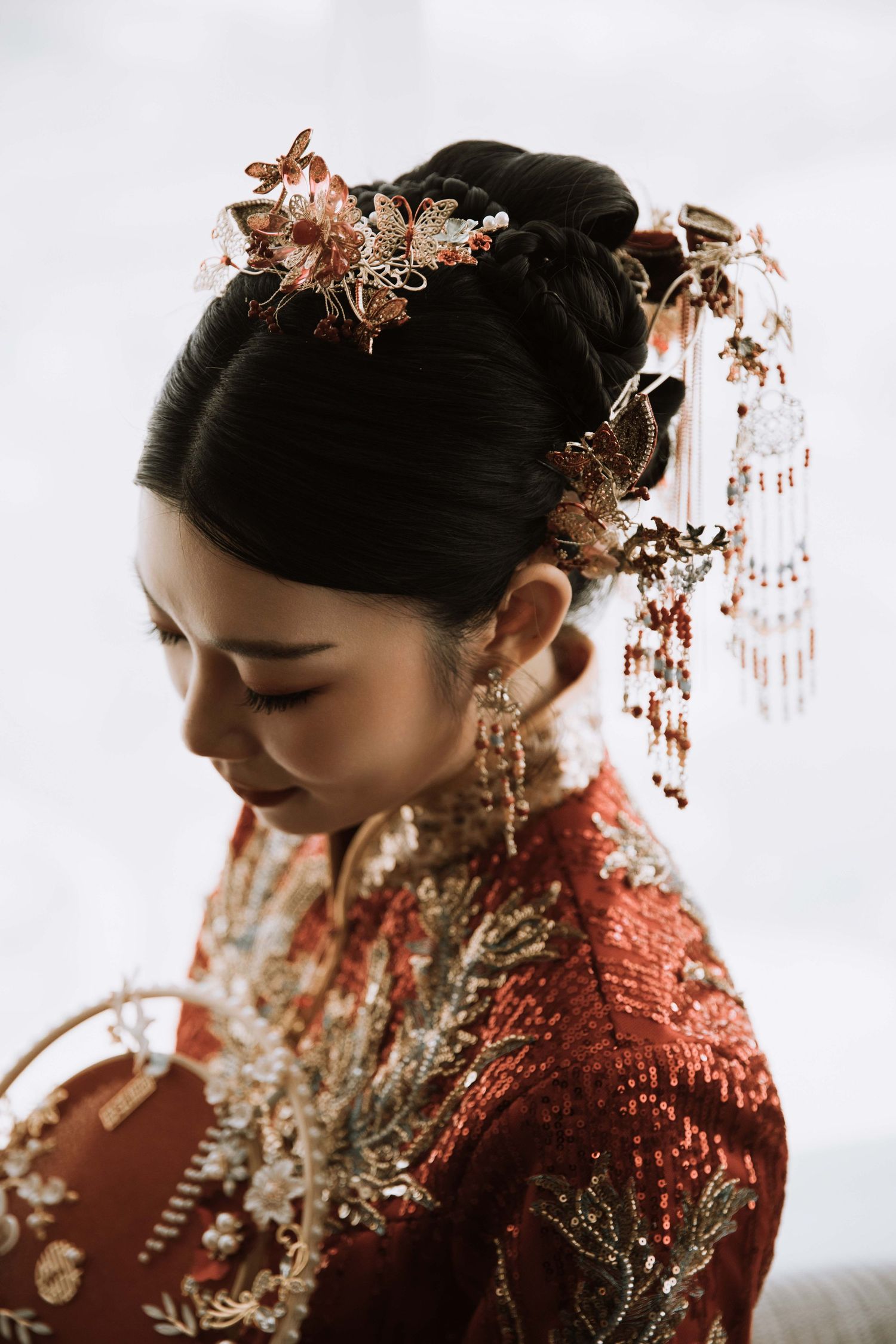 Close-up of intricate rose gold hair accessories and red traditional Chinese bridal attire.