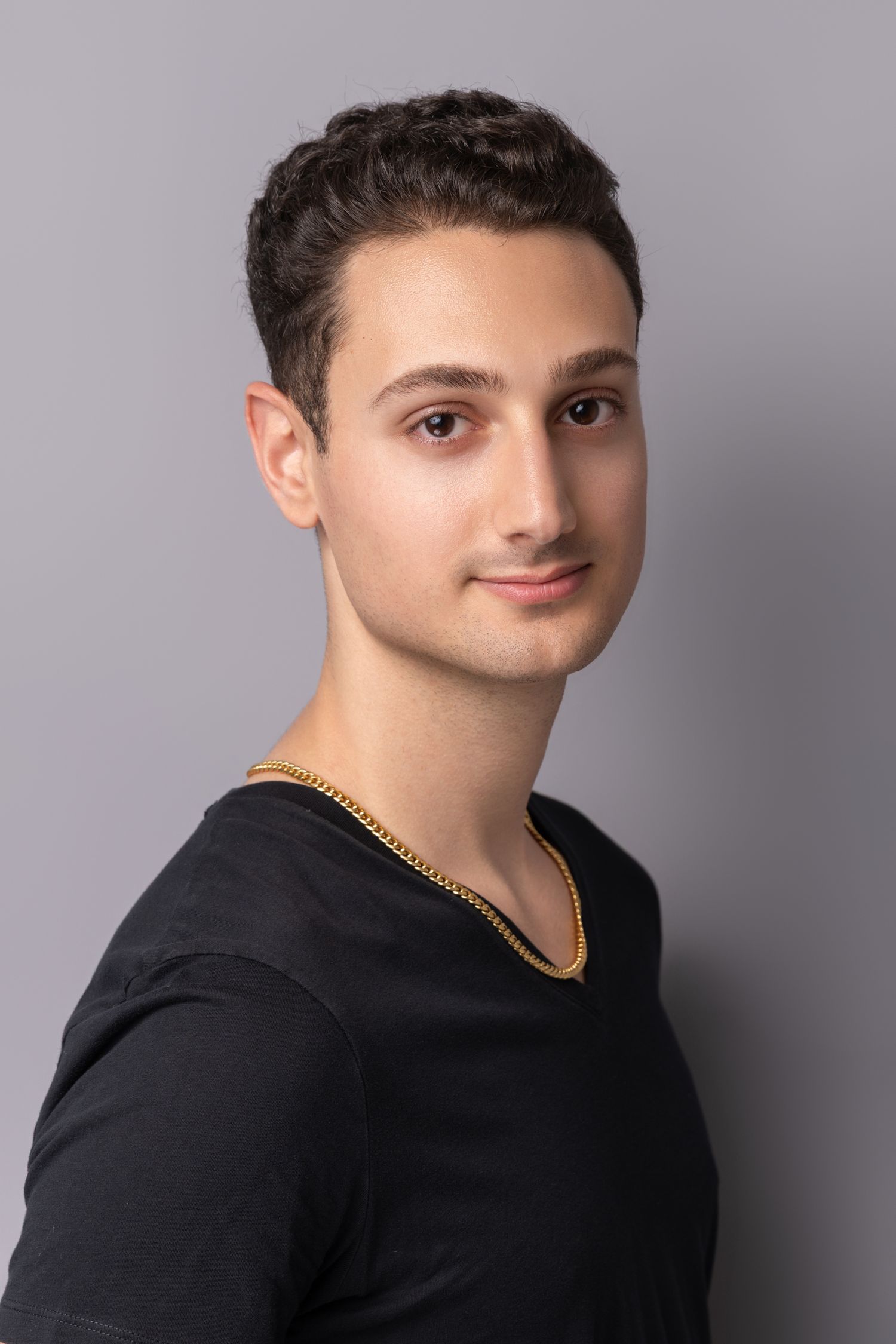 Professional studio portrait against grey background with dramatic lighting.