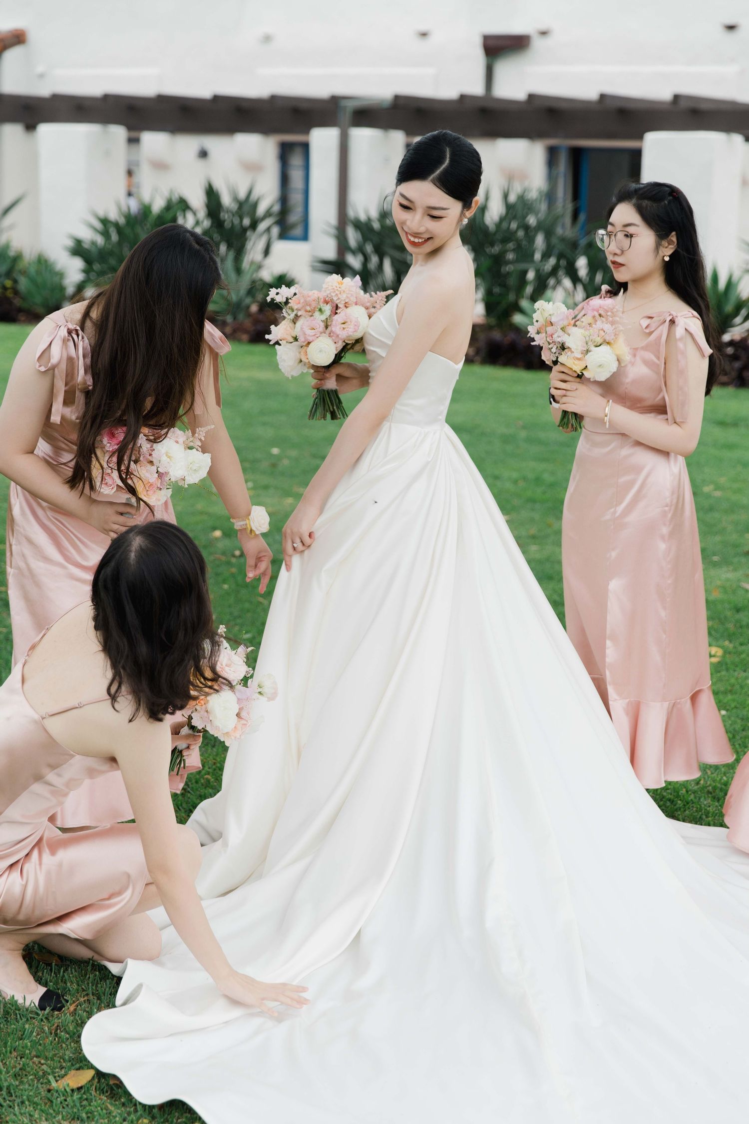 Wedding party in pink and white dresses posing together outdoors.