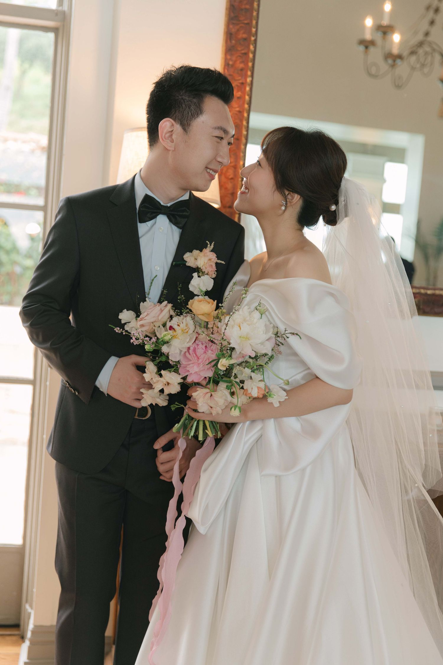 A couple shares an intimate moment with pink and white floral bouquets.