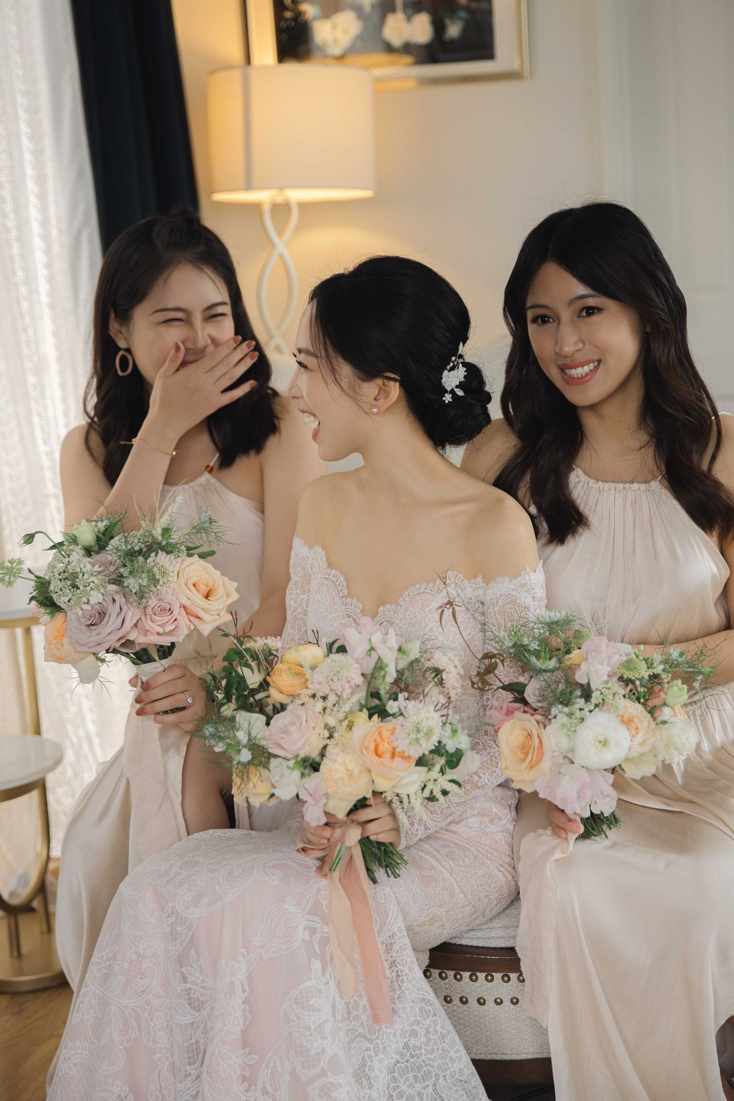 Candid moments of bridal party sharing laughter while holding romantic pastel floral arrangements.