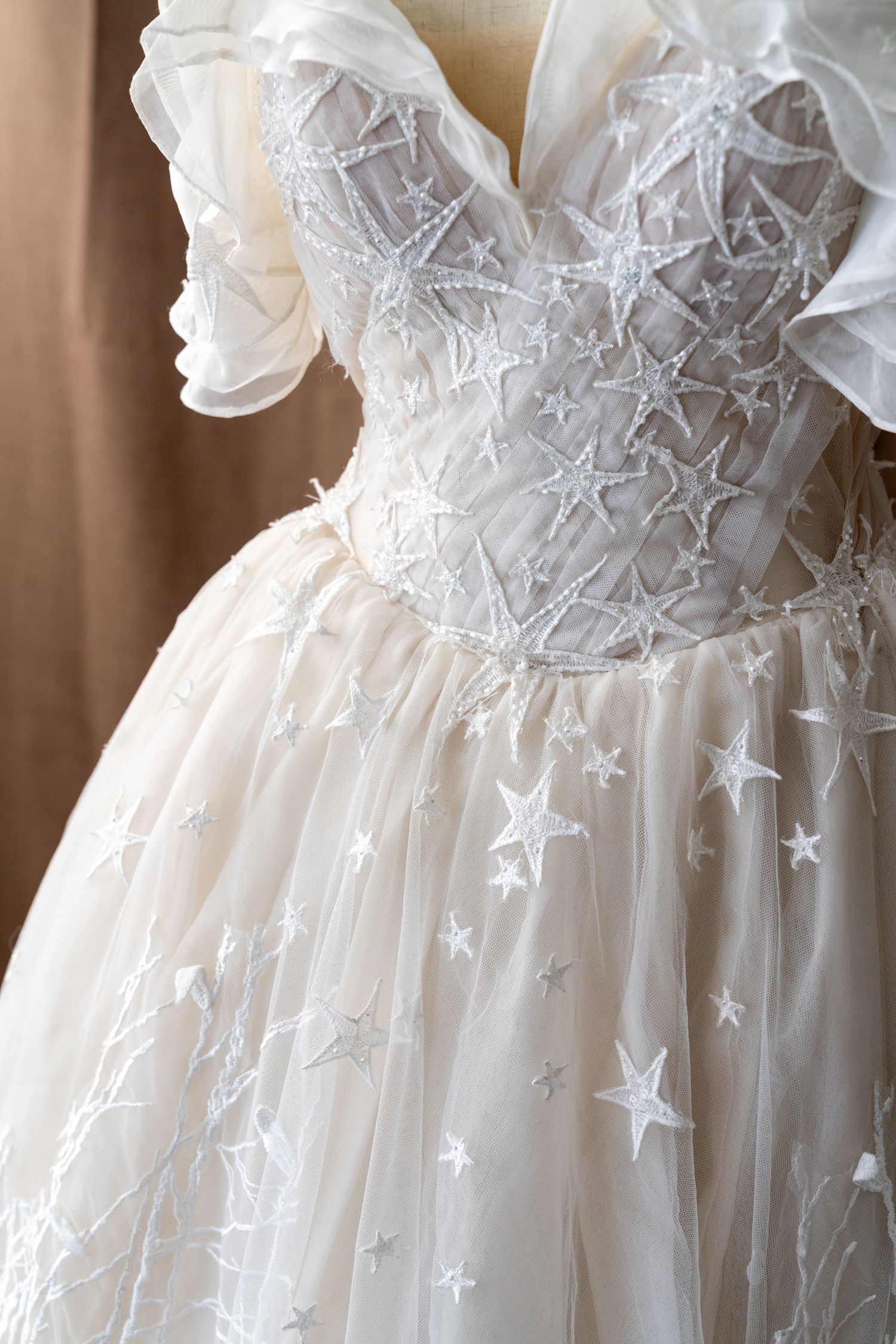 Close-up of wedding dress bodice showing ethereal star embellishments on sheer fabric.