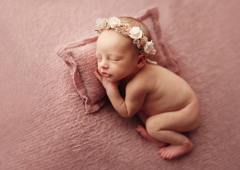 Peaceful newborn baby girl sleeping on a pink blanket wearing a delicate floral headband. Chesterfield va baby photographer
