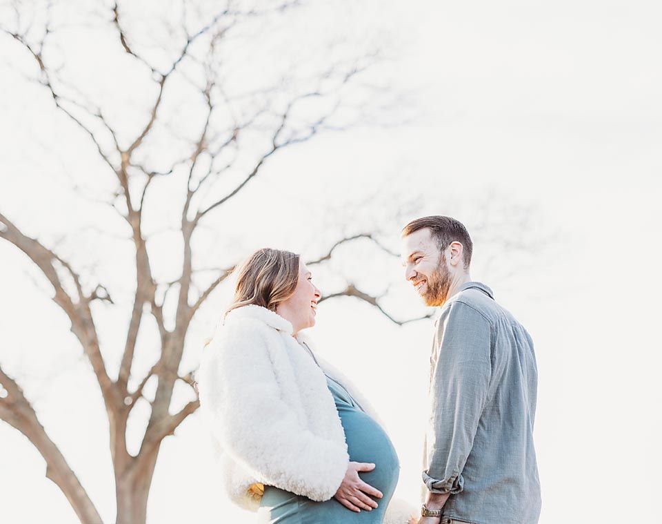 Happy couple sharing a tender moment during a winter maternity photo session outdoors.