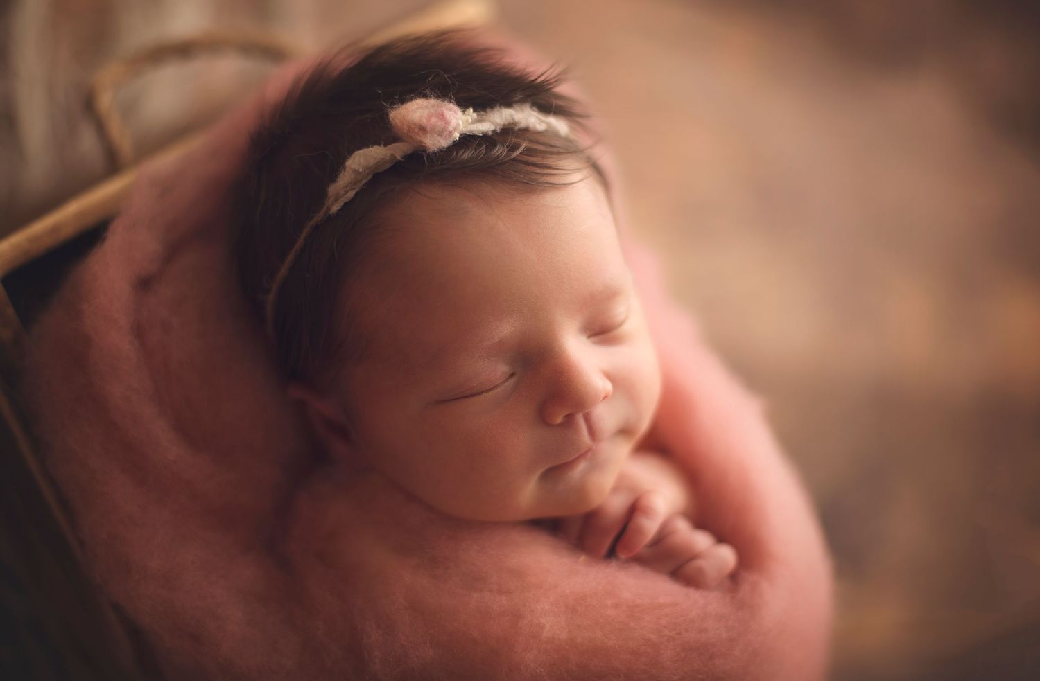Peaceful newborn baby girl sleeping in a pink fluffy bowl wearing a delicate floral headband Richmond newborn photographer