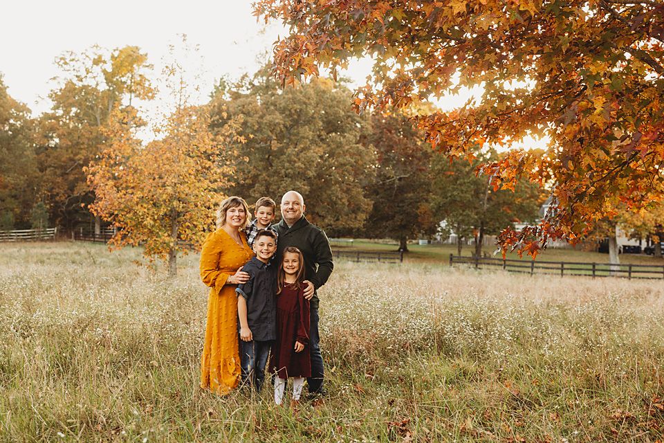 Family of six posing together in an autumn field surrounded by colorful fall foliage Richmond VA family photography. Midlothian, Petersburg,