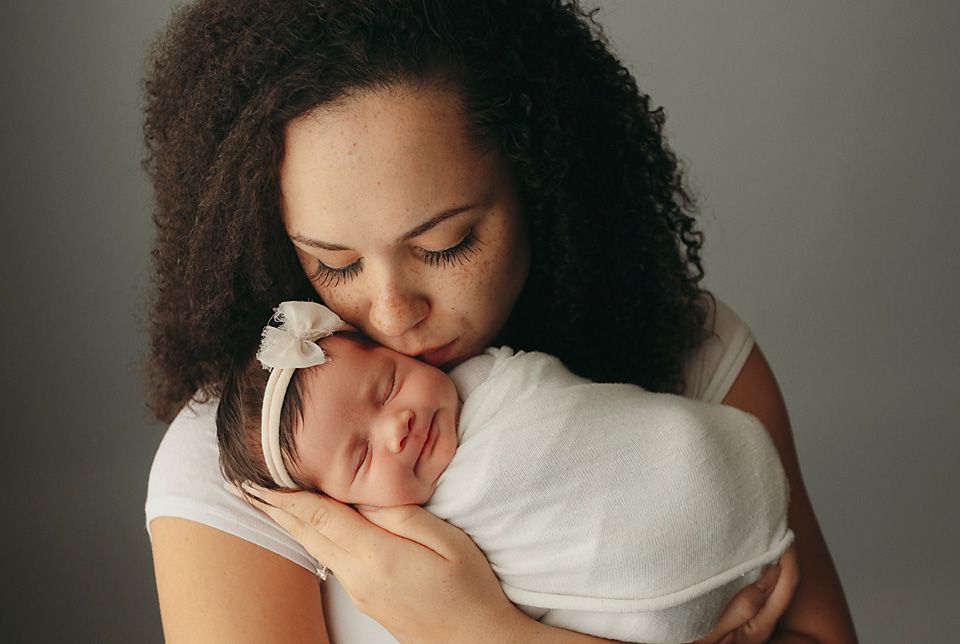 Mother kissing swaddled newborn baby with curly hair portraitnewborn photographer Richmond Chesterfield midlothian Petersburg glen Allen sho