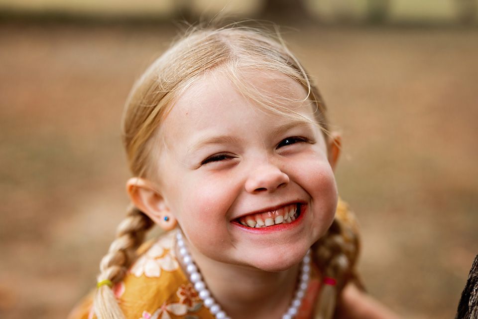 Smiling young girl with blonde braids and a pearl necklace in a joyful portrait. children's portraiture Richmond va midlothian