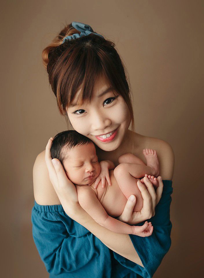 Smiling mother in blue top holding her sleeping newborn baby newborn photographer Richmond Chesterfield midlothian Petersburg