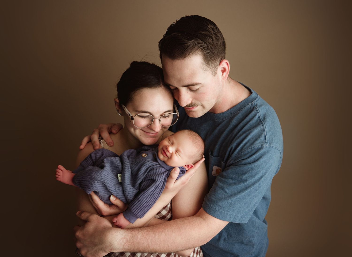 New parents tenderly cradling their sleeping newborn baby in a professional studio portrait photo. Chesterfield, va