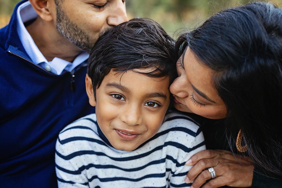 Parents lovingly kissing their young son on both cheeks outdoors Richmond VA family photography. Midlothian, Petersburg, Glen Allen