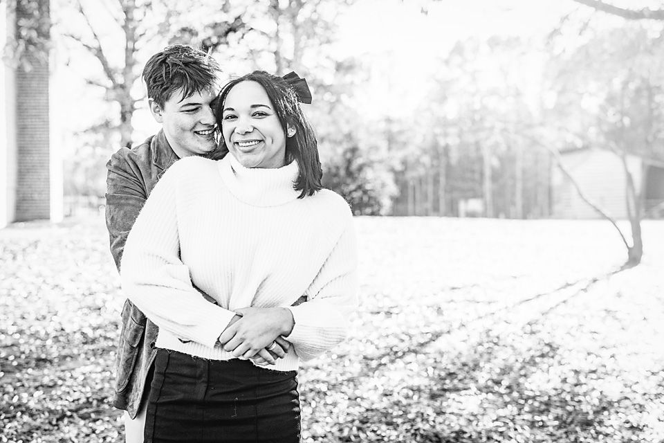 Black and white photo of a couple embracing outdoors in a park during autumnRichmond va family photography.
