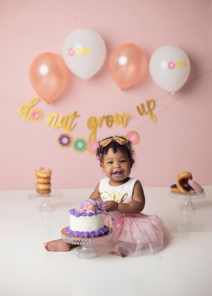 Baby girl celebrating first birthday smashing purple cake at donut grow up themed party. Chesterfield VA studio