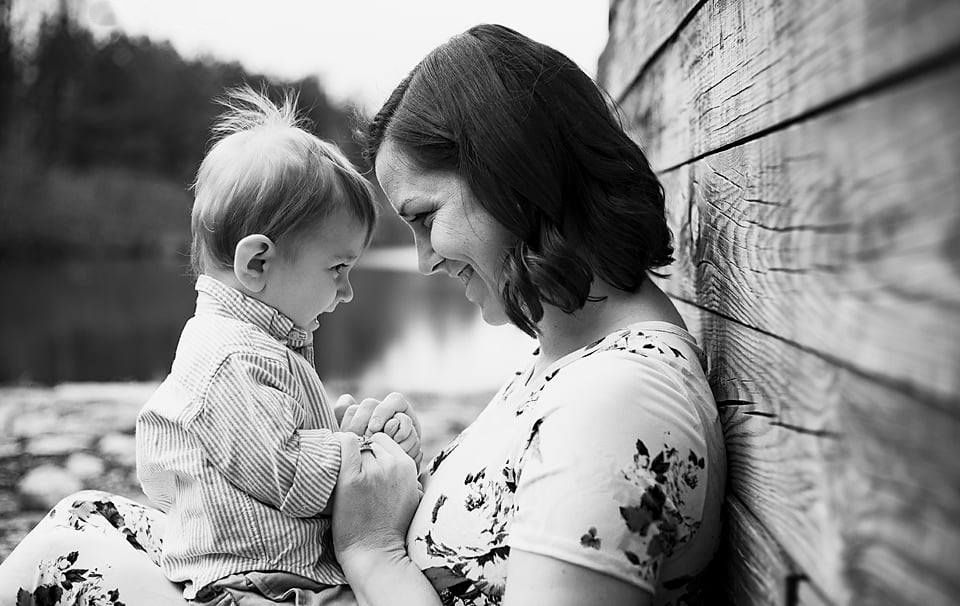 Black and white photo of a mother and toddler sharing a tender moment by a wooden wall. Midlothian Mines park photography