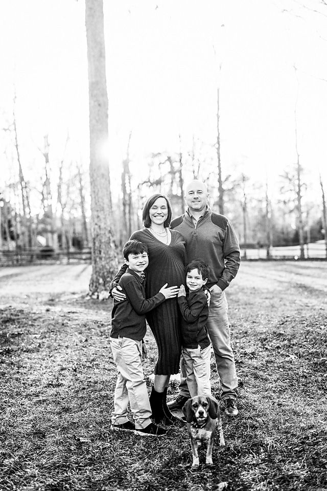 Black and white family portrait with two boys, a dog, and expecting parents outdoors. Maternity photography Richmond, Petersburg, midlothian
