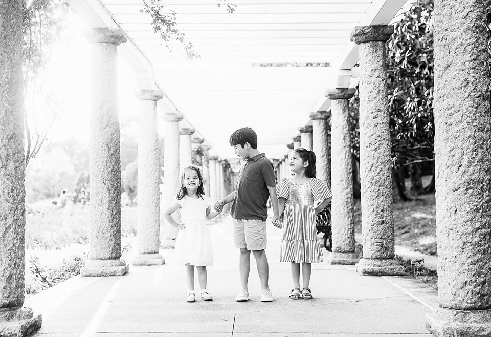 Three children walking under columns in black and white photo Richmond family photographer, midlothian, glen Allen, short pump
