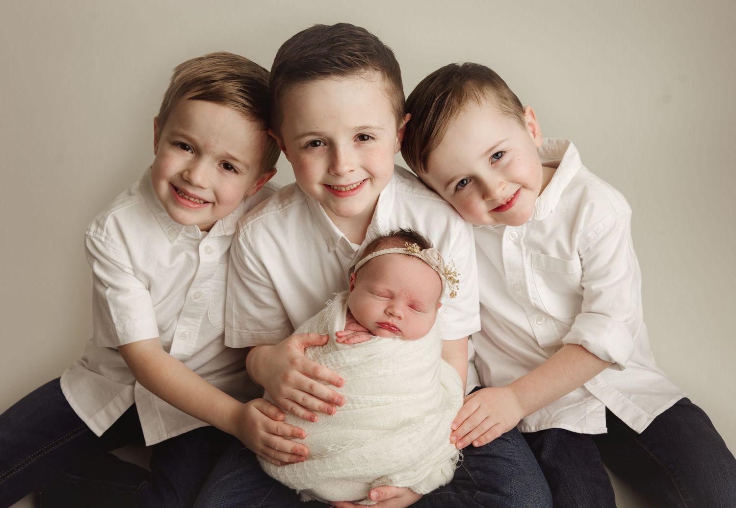 Three smiling boys in white shirts posing with their sleeping newborn baby sister. infant Richmond photography