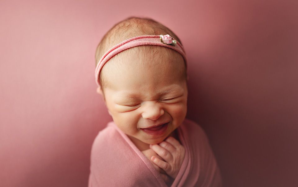 Smiling newborn baby wrapped in pink swaddle with newborn photographer Richmond Chesterfield midlothian Petersburg glen Allen short pump