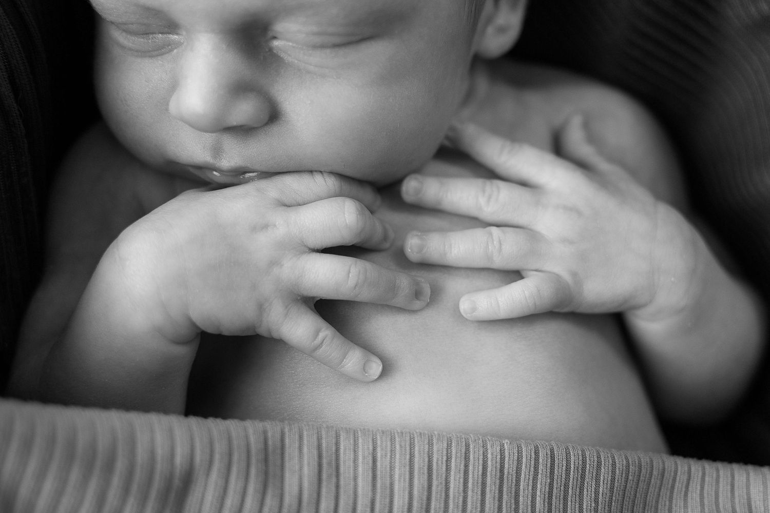 Black and white close-up photo showing hands gently touching skin in an artistic composition.
