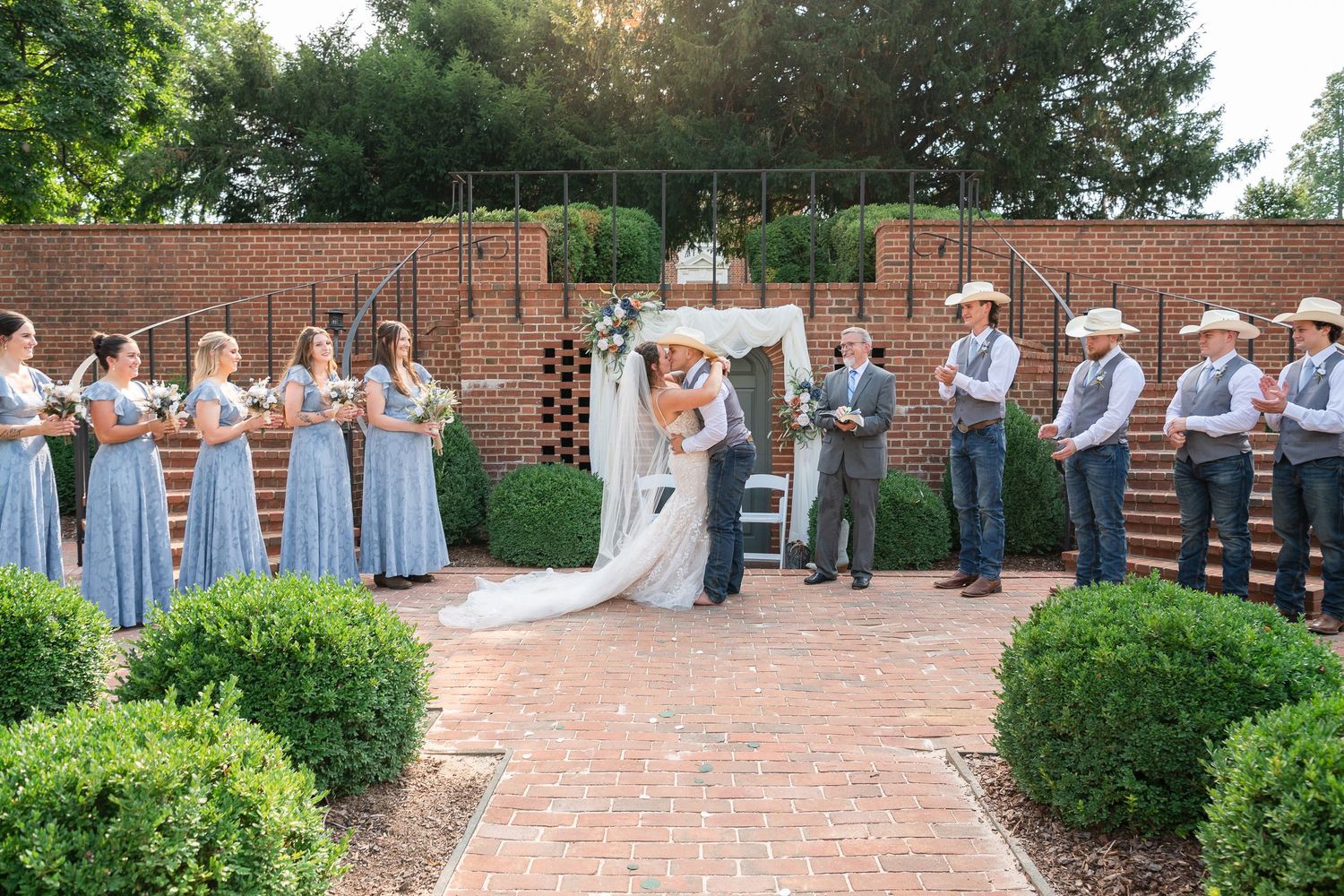 Maryland Wedding party lined up outdoors on brick patio with greenery and matching light blue dresses for summer celebration.