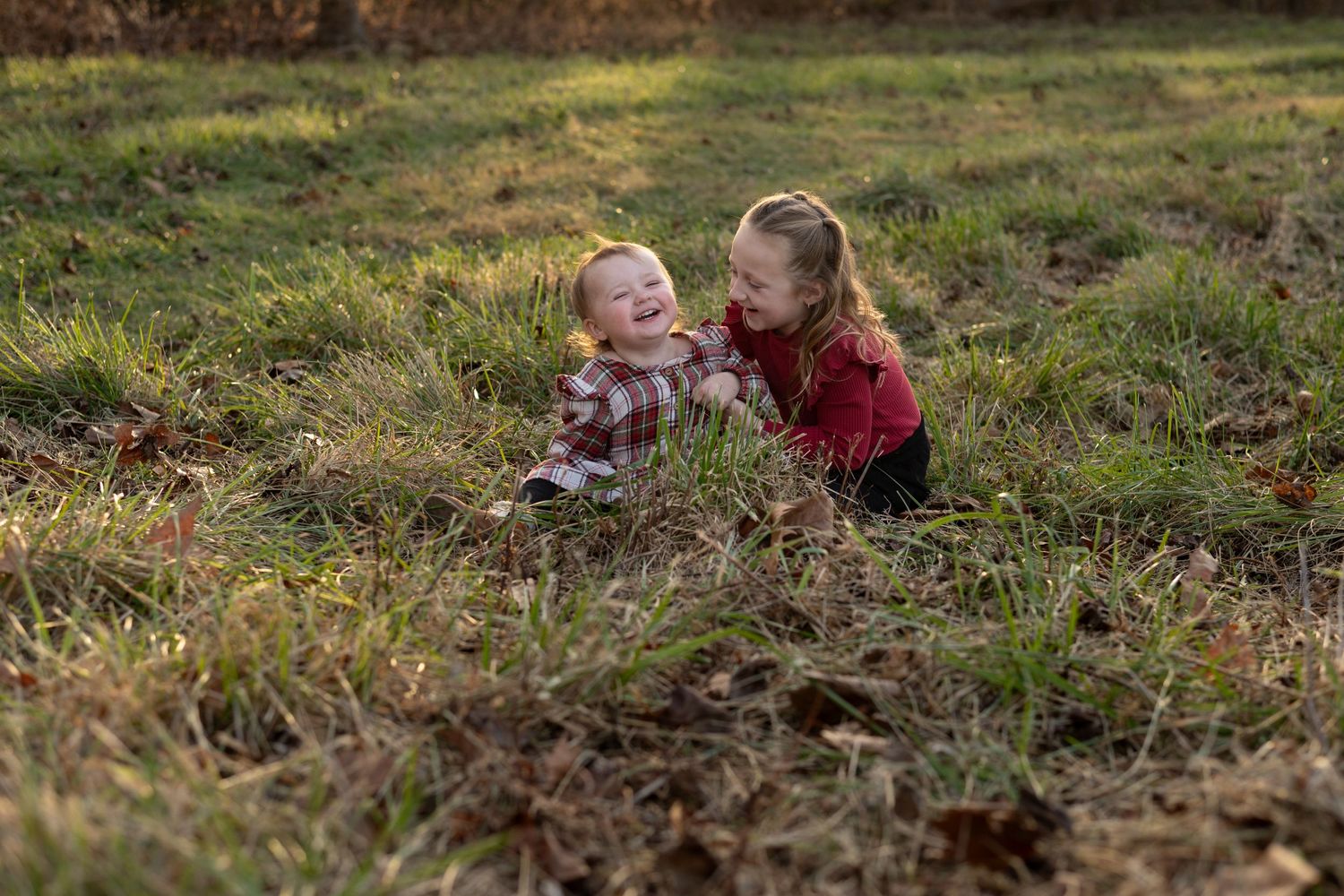 Two children playing and laughing together in autumn leaves.