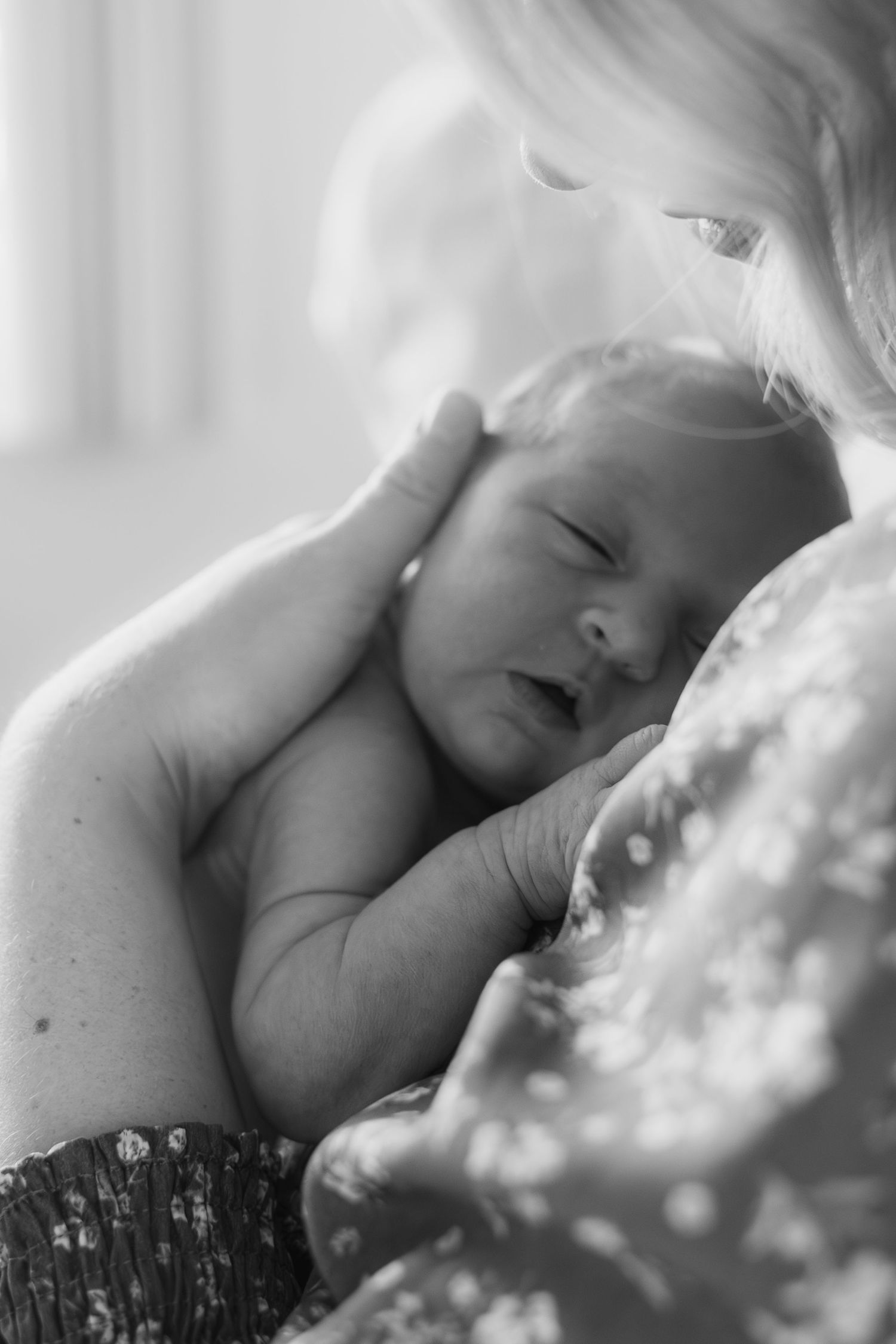 A sleeping baby rests peacefully on moms chest with dappled sunlight creating a dreamy atmosphere.
