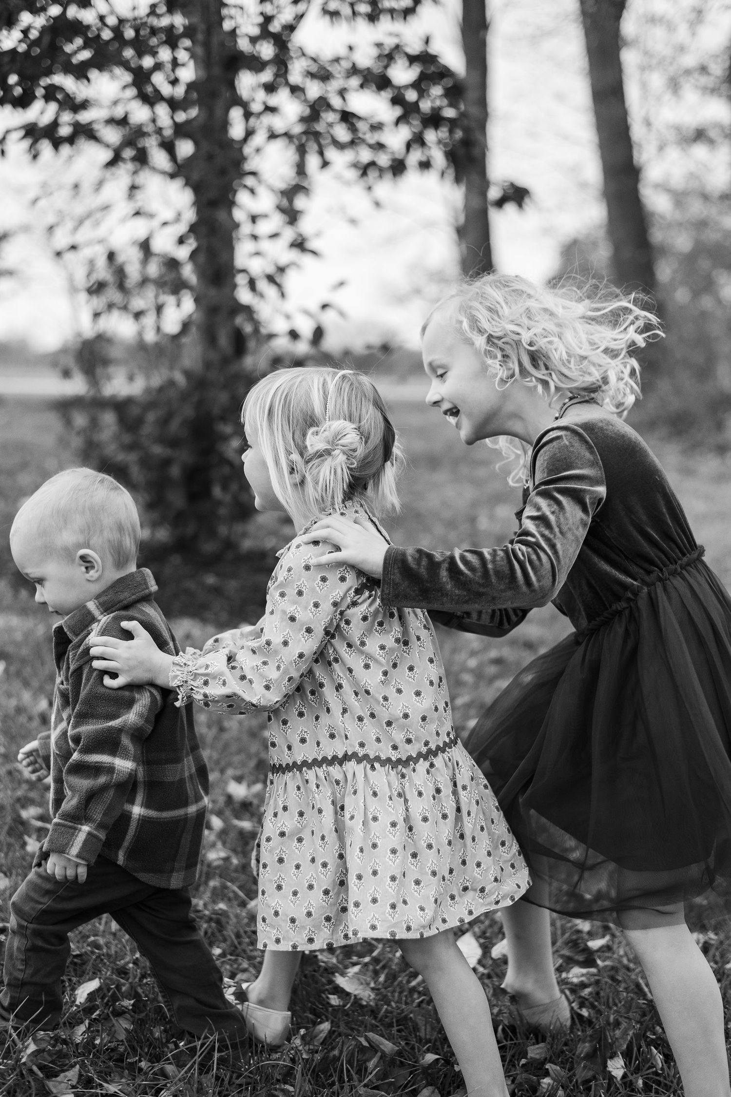 A series of black and white photos showing two children playing and laughing together outdoors.