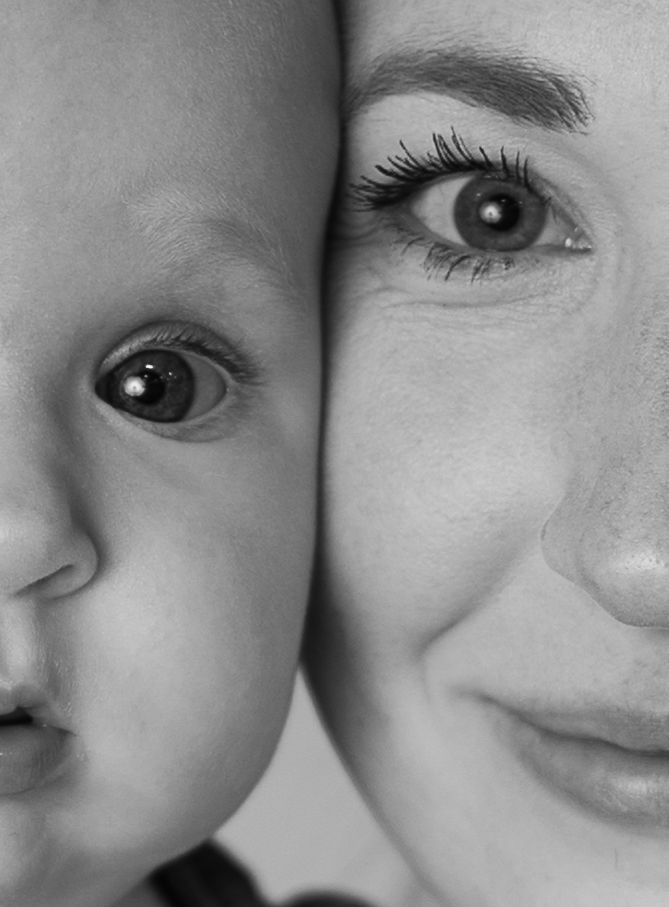 Black and white close-up portrait of a mother and baby cheek to cheek, showing generational contrast.