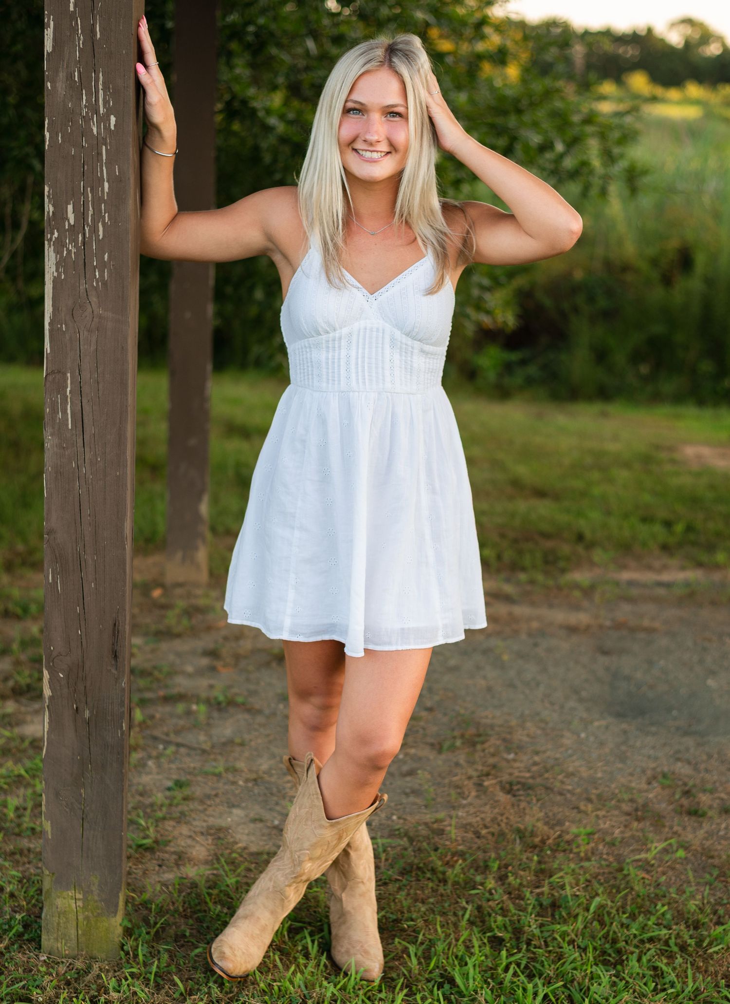 A joyful scene in an outdoor setting with someone wearing a white summer dress and tan boots on a rustic path.