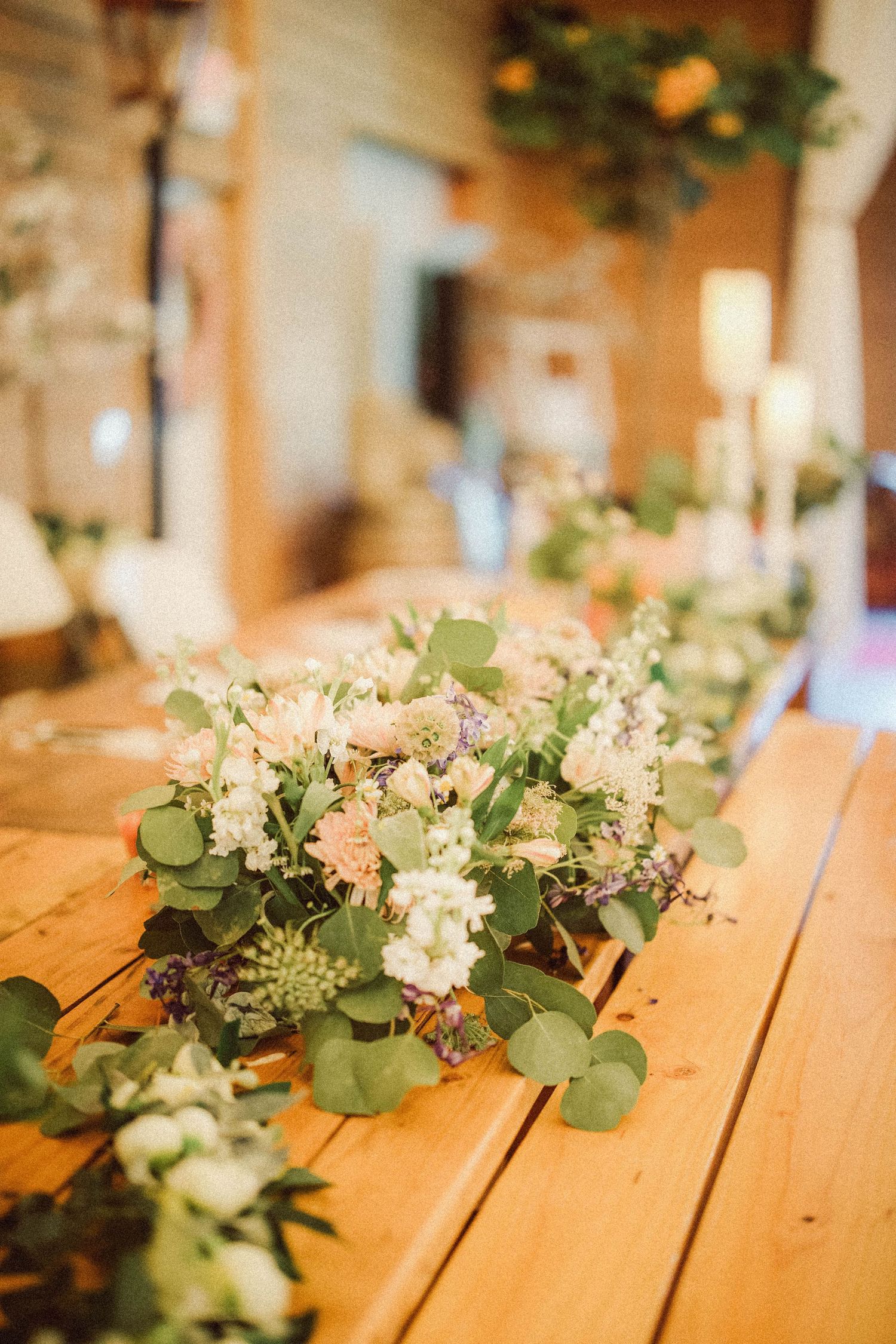 Elegant wedding table decorated with fresh floral arrangements of white and pink blooms with eucalyptus greenery.