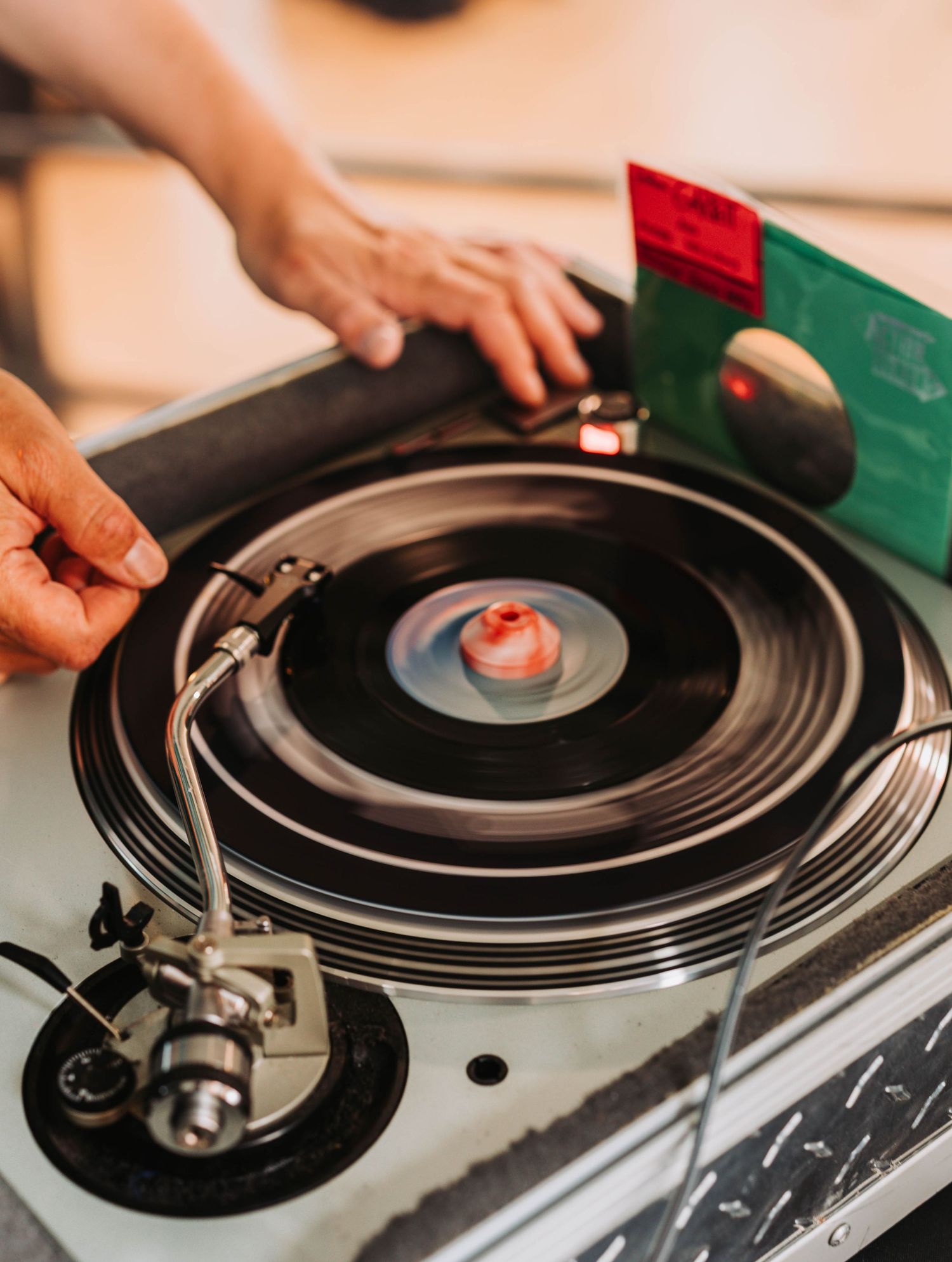 Close-up of hands placing a vinyl record on a spinning turntable at a wedding reception.