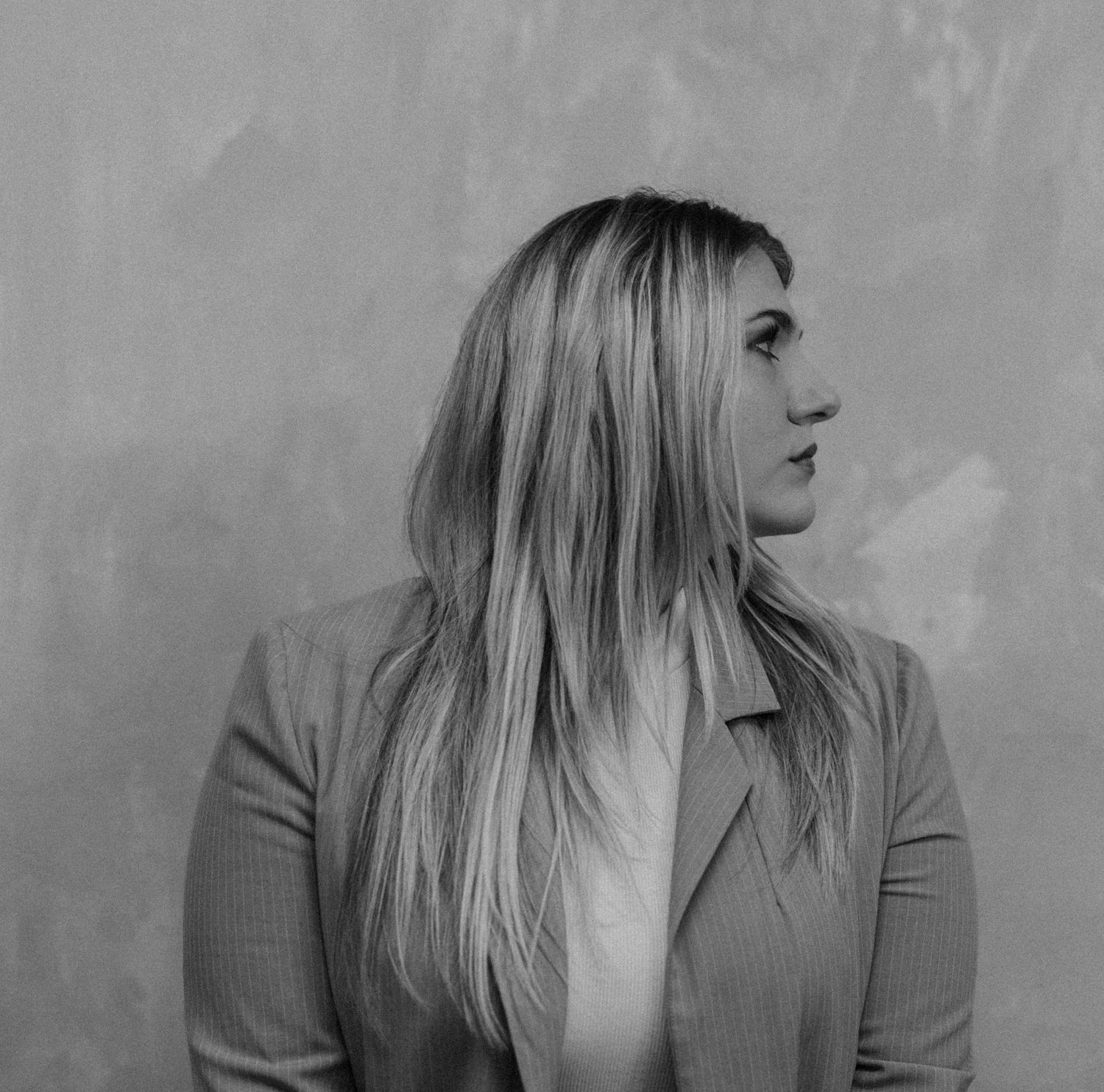Black and white side profile portrait of blonde woman in blazer looking away.