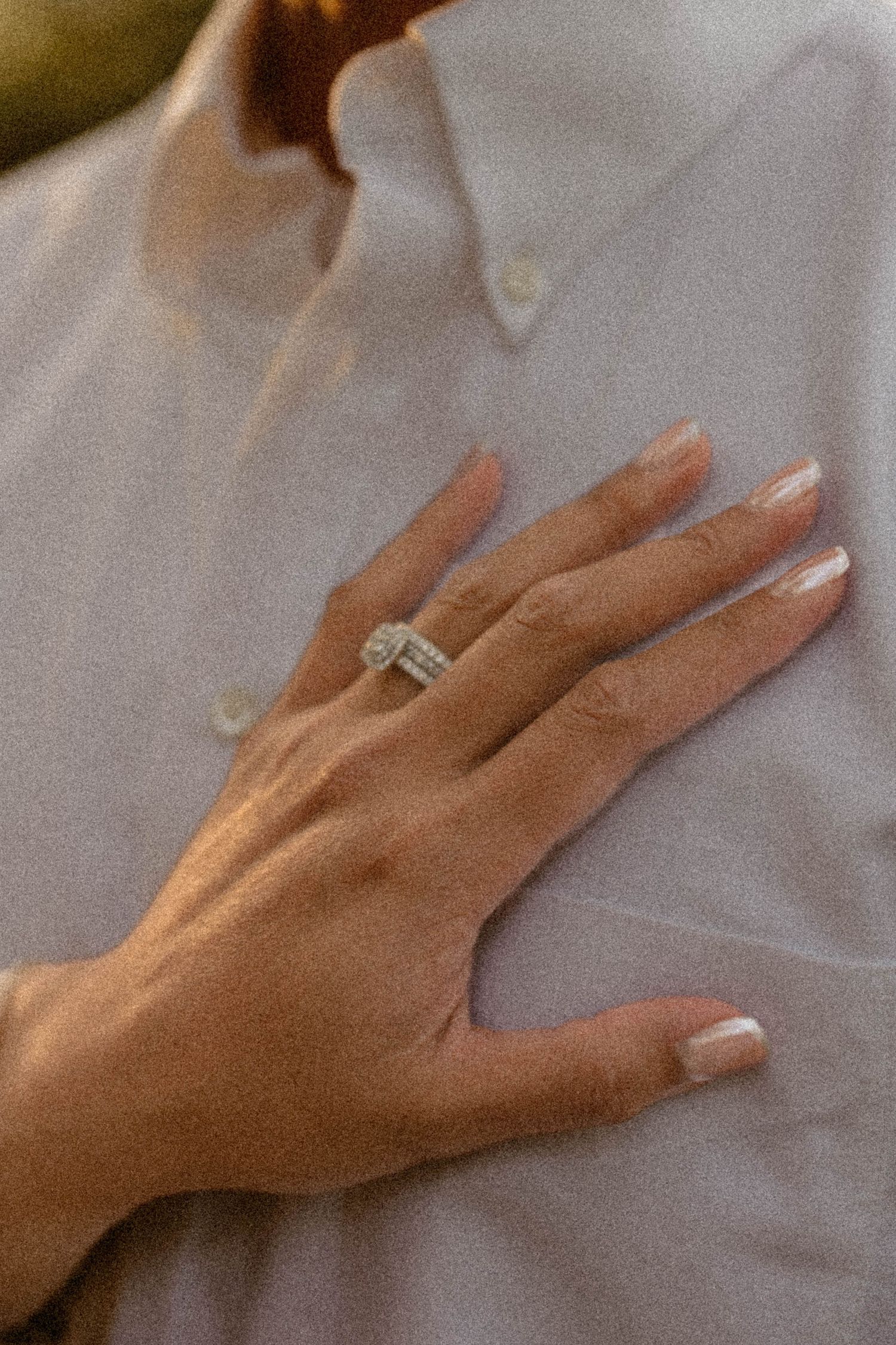 Close-up of a bride's hand displaying a diamond engagement ring and wedding band on her ring finger.