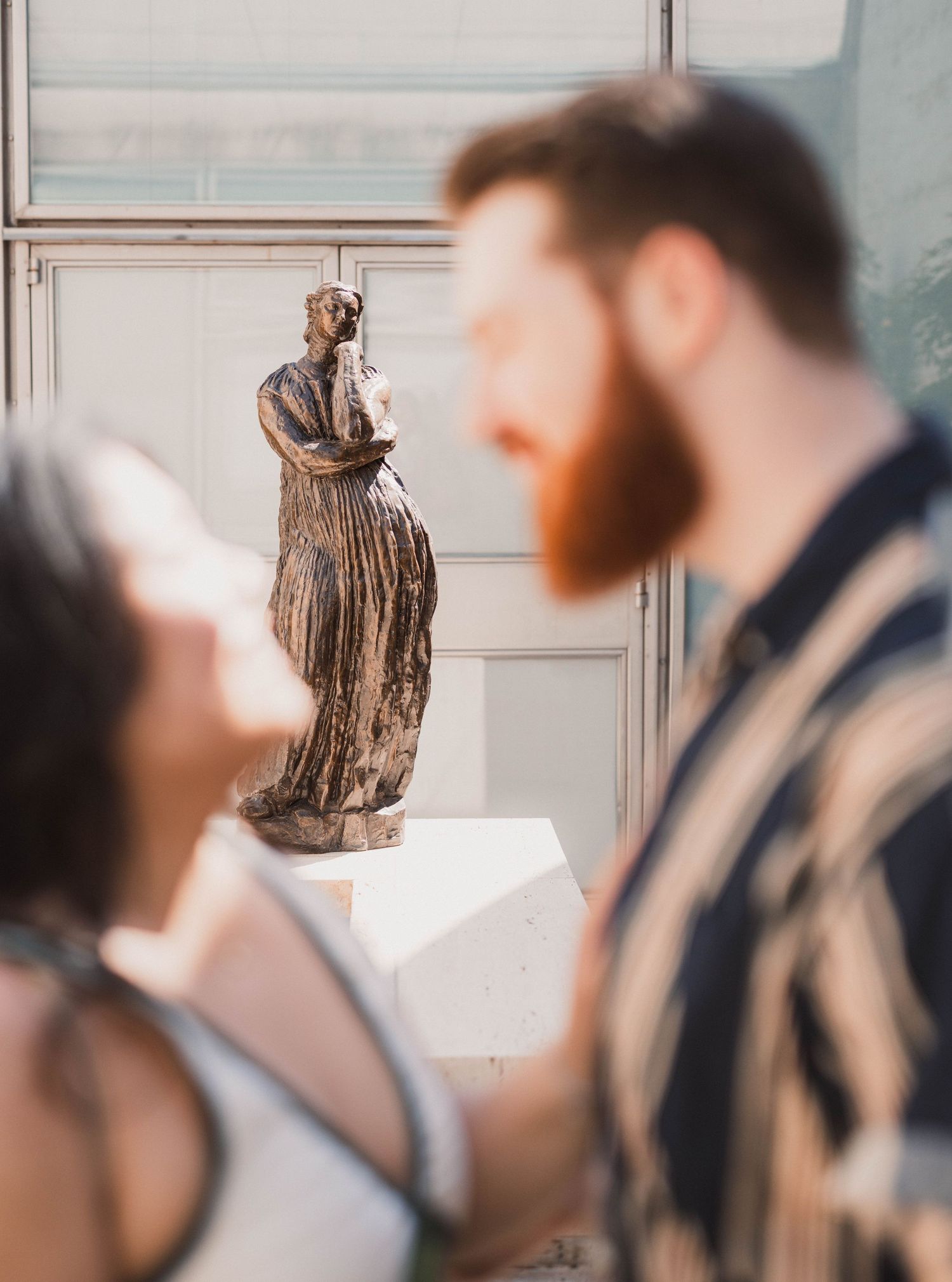Couple viewing bronze sculpture statue at art museum gallery exhibition.