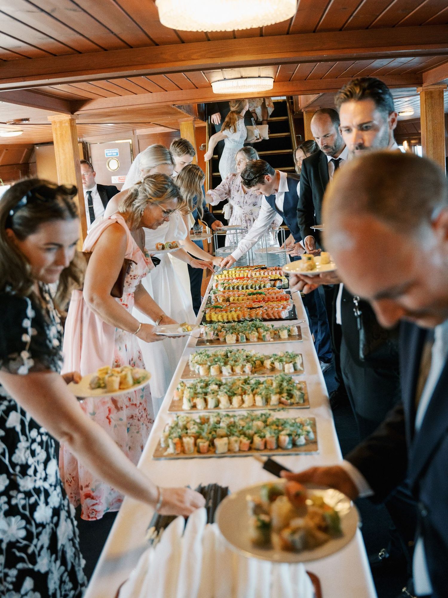 Guests serving themselves at an elegant wedding buffet table filled with colorful appetizers and hors d'oeuvres.