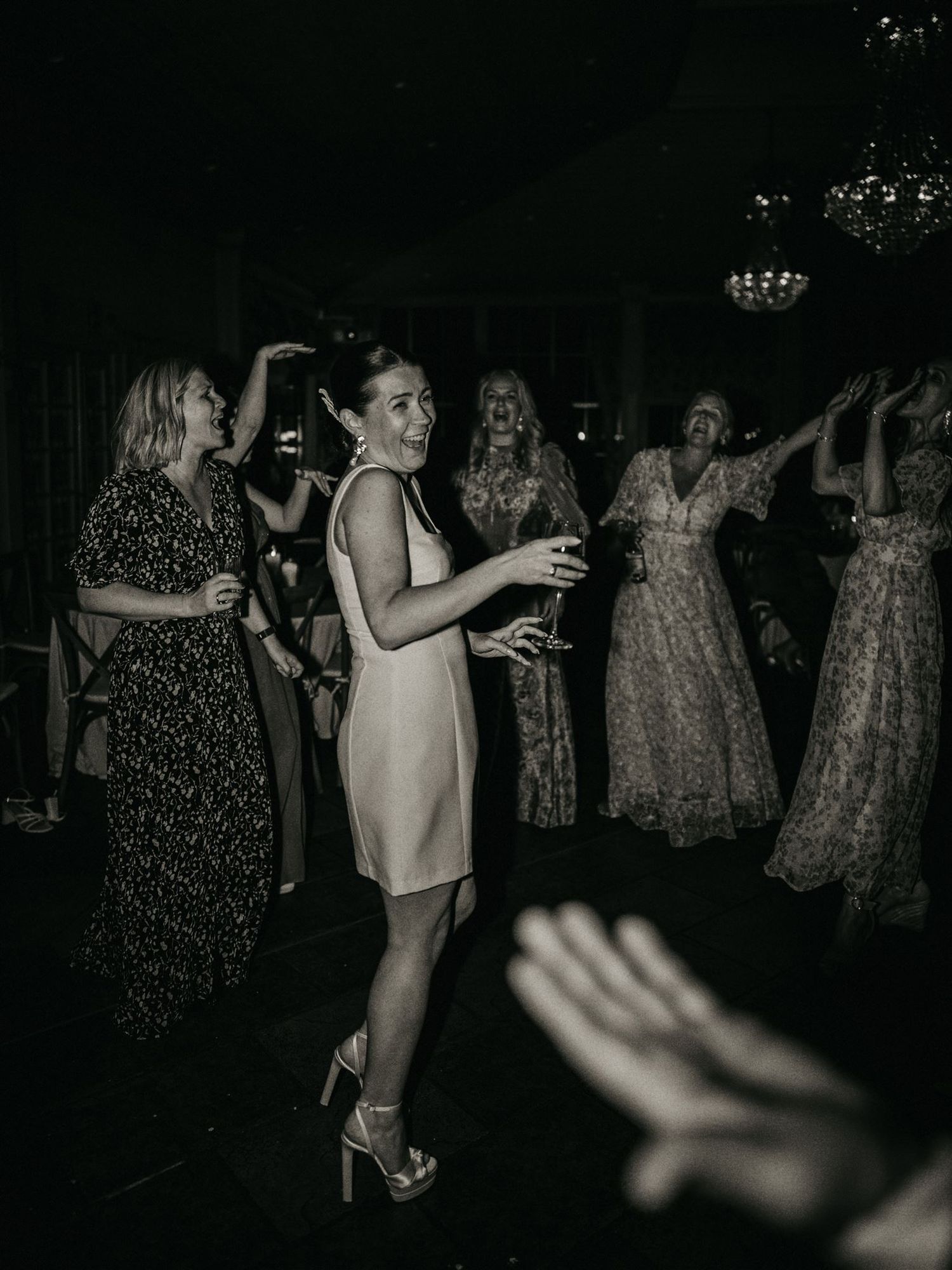 Guests dancing joyfully at an elegant wedding reception in black and white photography.