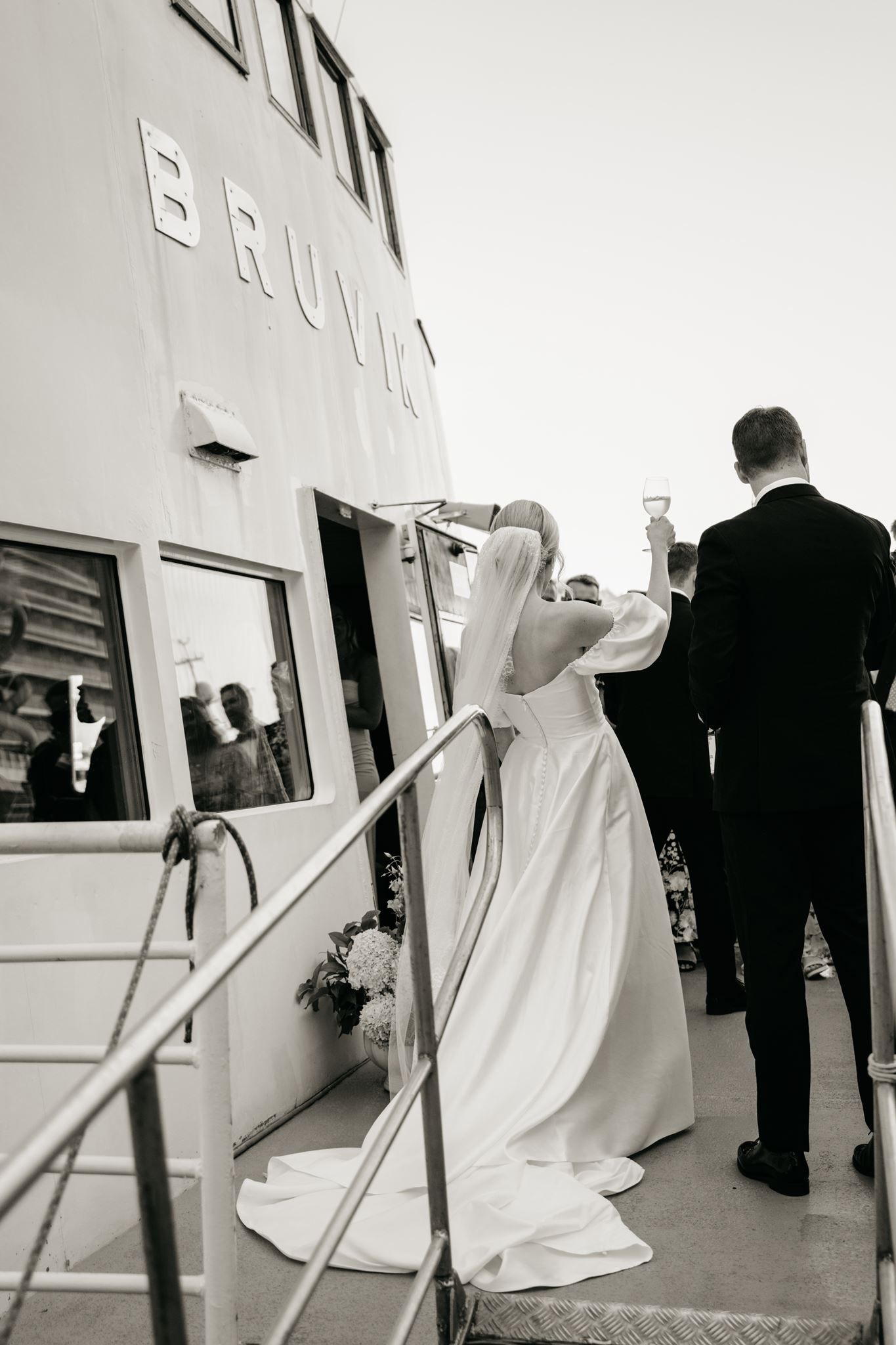 Bride and groom boarding a vessel named Brulia on their wedding day in a black and white photo.