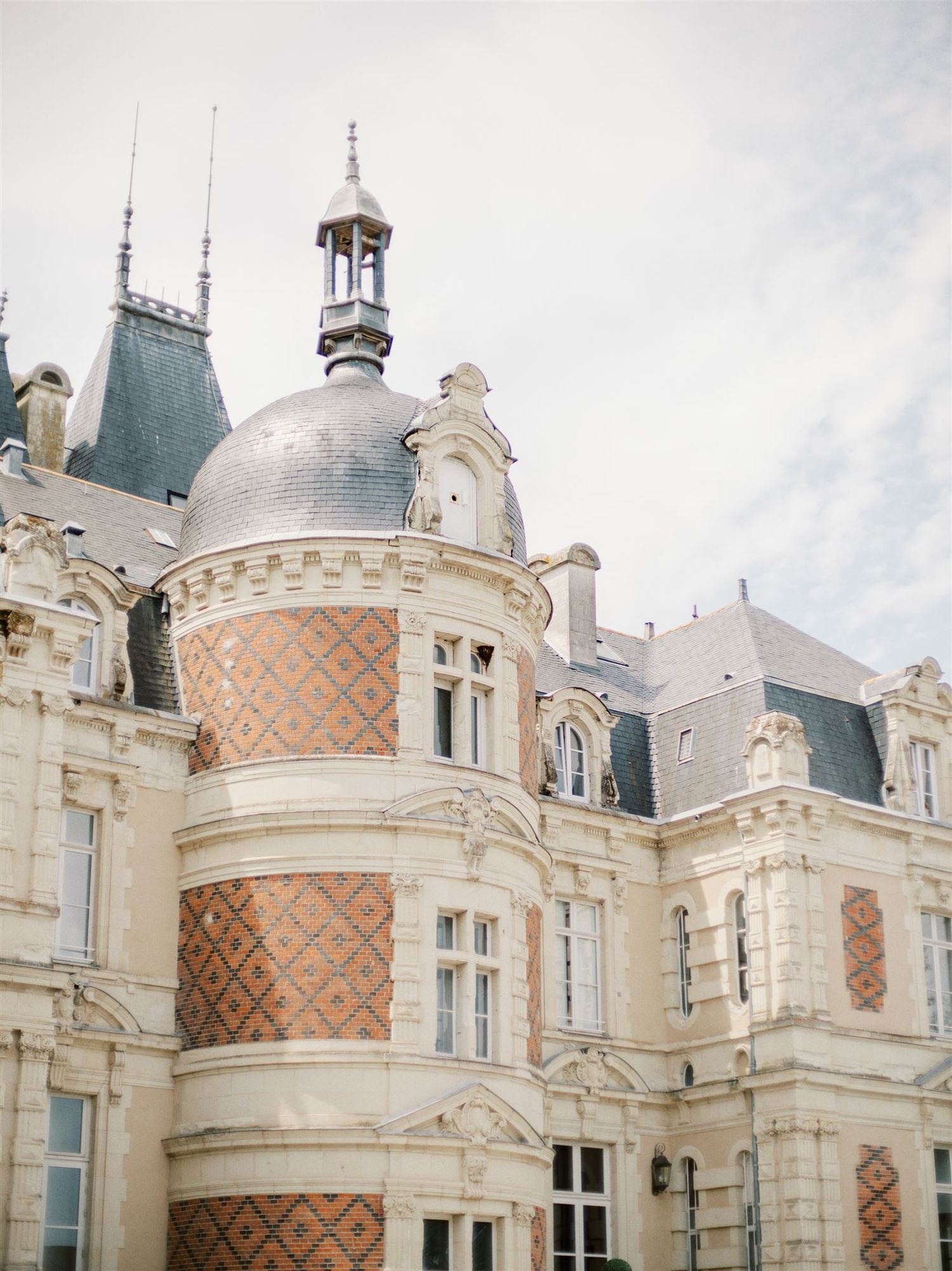 Ornate French chateau with decorative dome roof and patterned stone facade details.
