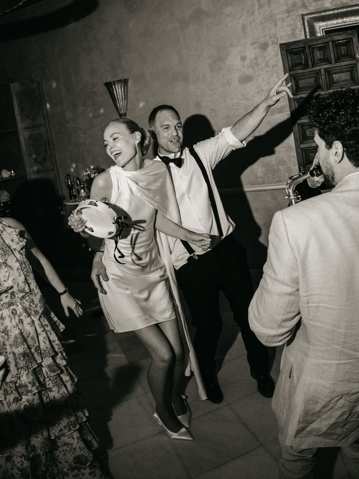 Black and white photo of a joyful bride and groom dancing energetically at their wedding reception.