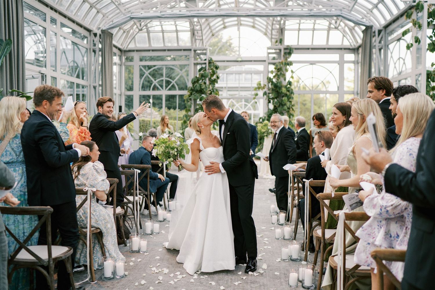 Bride and groom share a kiss at the altar inside a beautiful glass greenhouse wedding ceremony.