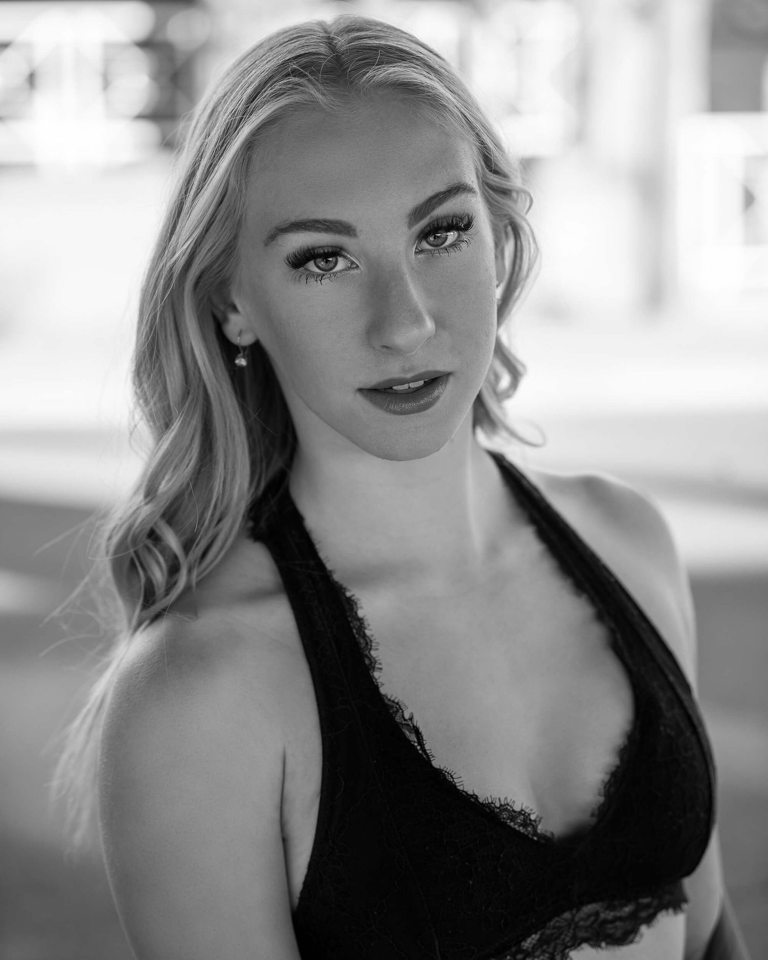 Black and white portrait of blonde woman in lace top with dramatic makeup.