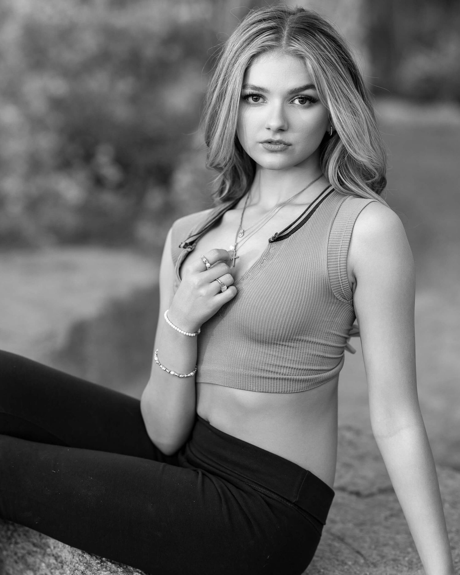 Young woman in crop top and black leggings poses outdoors in black and white portrait photography.