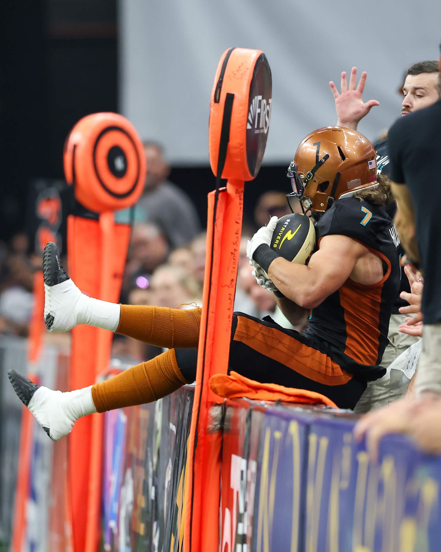 Indoor football player wearing number 7 crashes into padded goal post barrier.