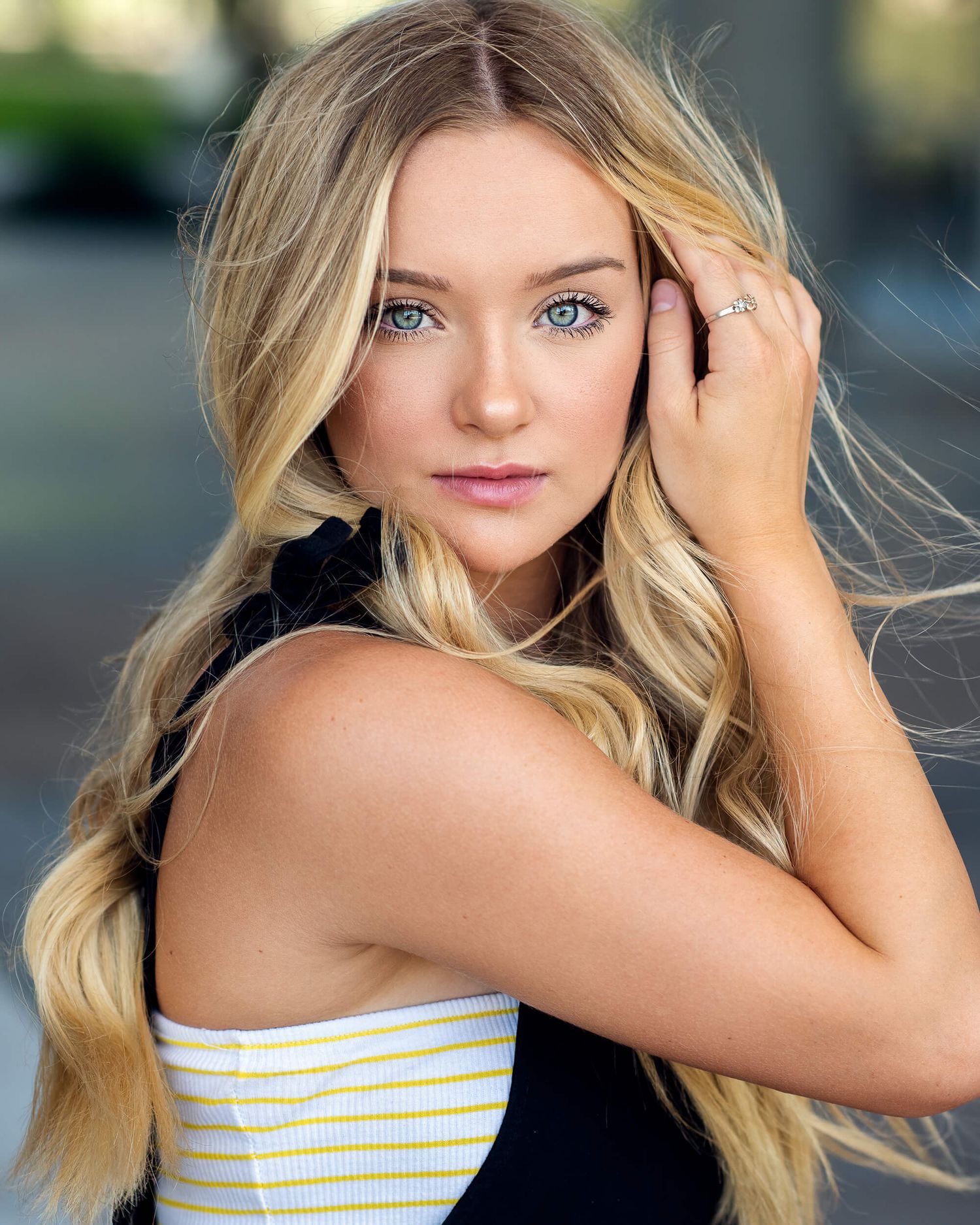 Blonde woman with blue eyes and wavy hair posing for a professional headshot in a striped top.