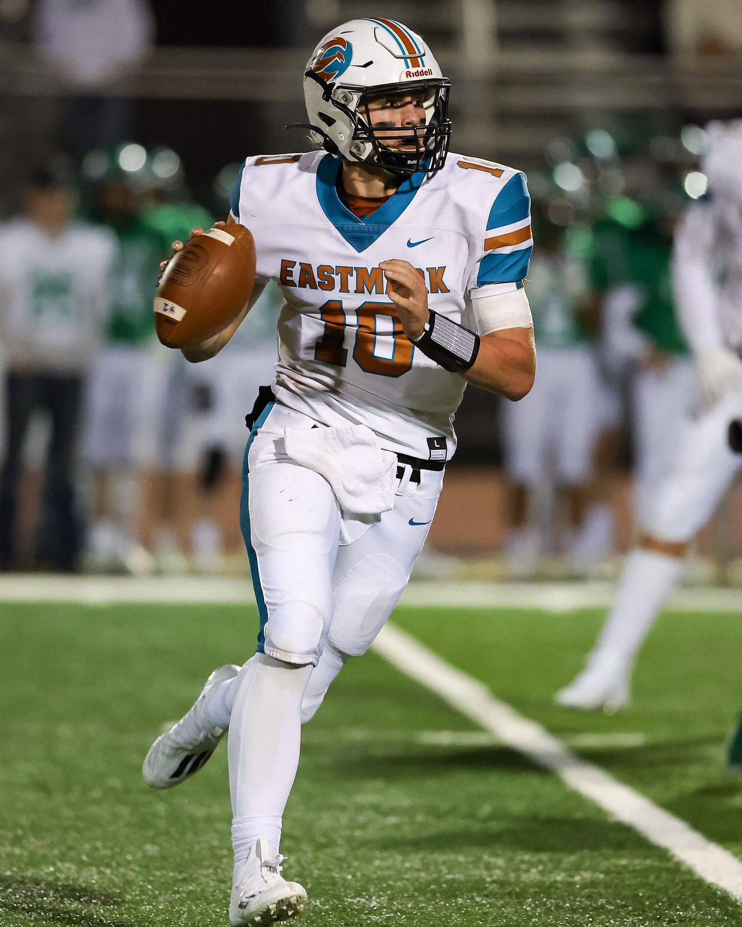 Eastmark football quarterback number 10 scrambles with the ball during a night game.