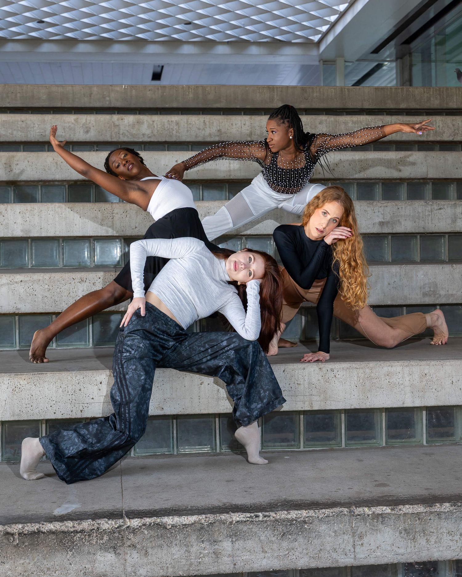 Four female dancers posing dynamically on concrete stadium steps.
