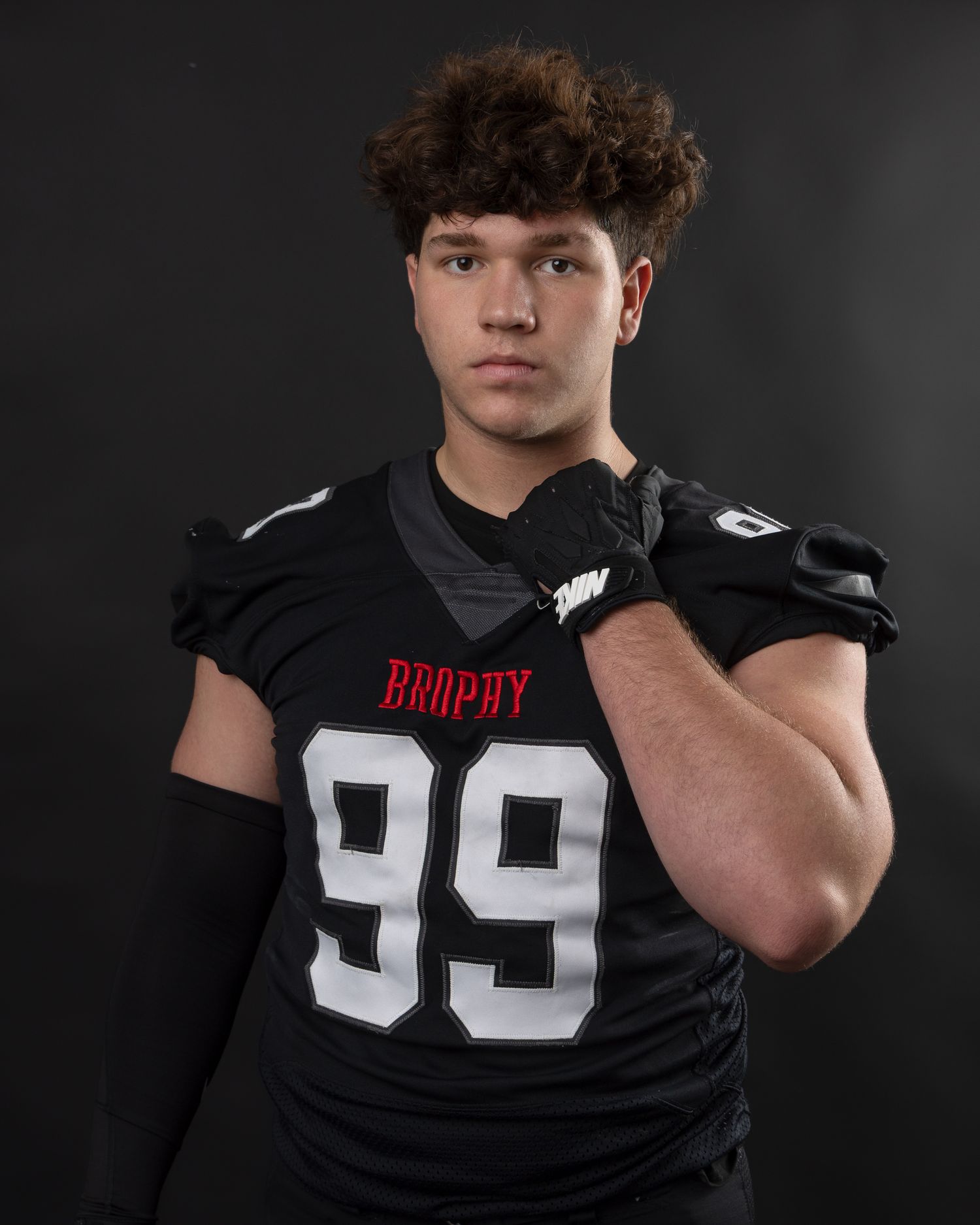 High school football player in Brophy jersey number 99 poses in black uniform for sports portrait.