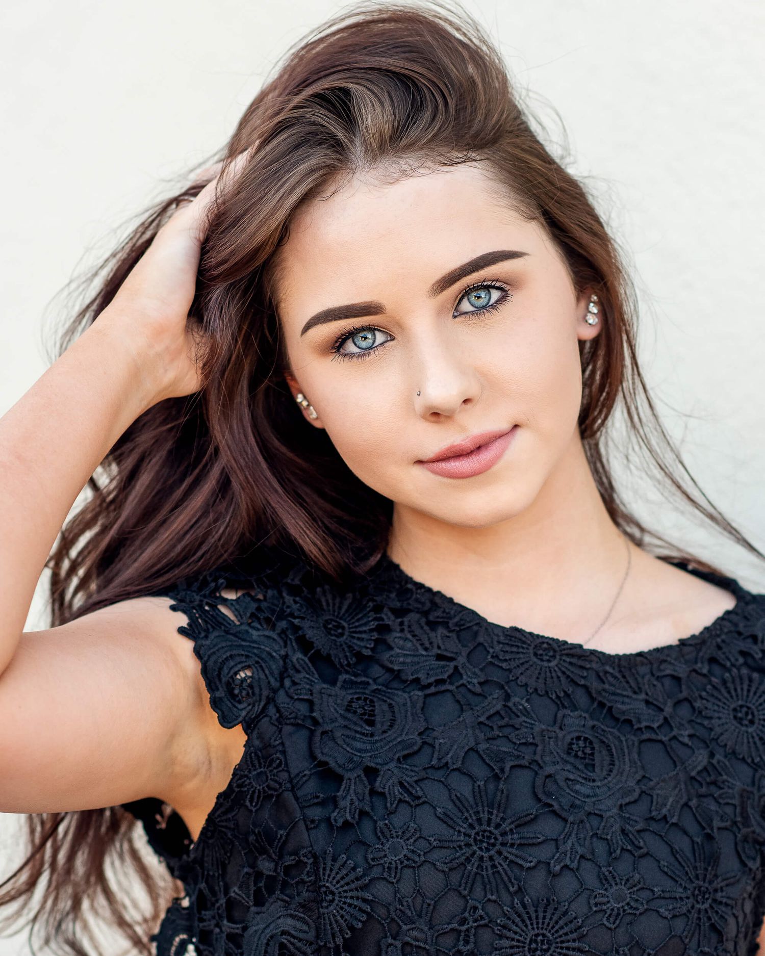 Beautiful young woman with blue eyes and dark hair in black lace top posing for portrait photo.
