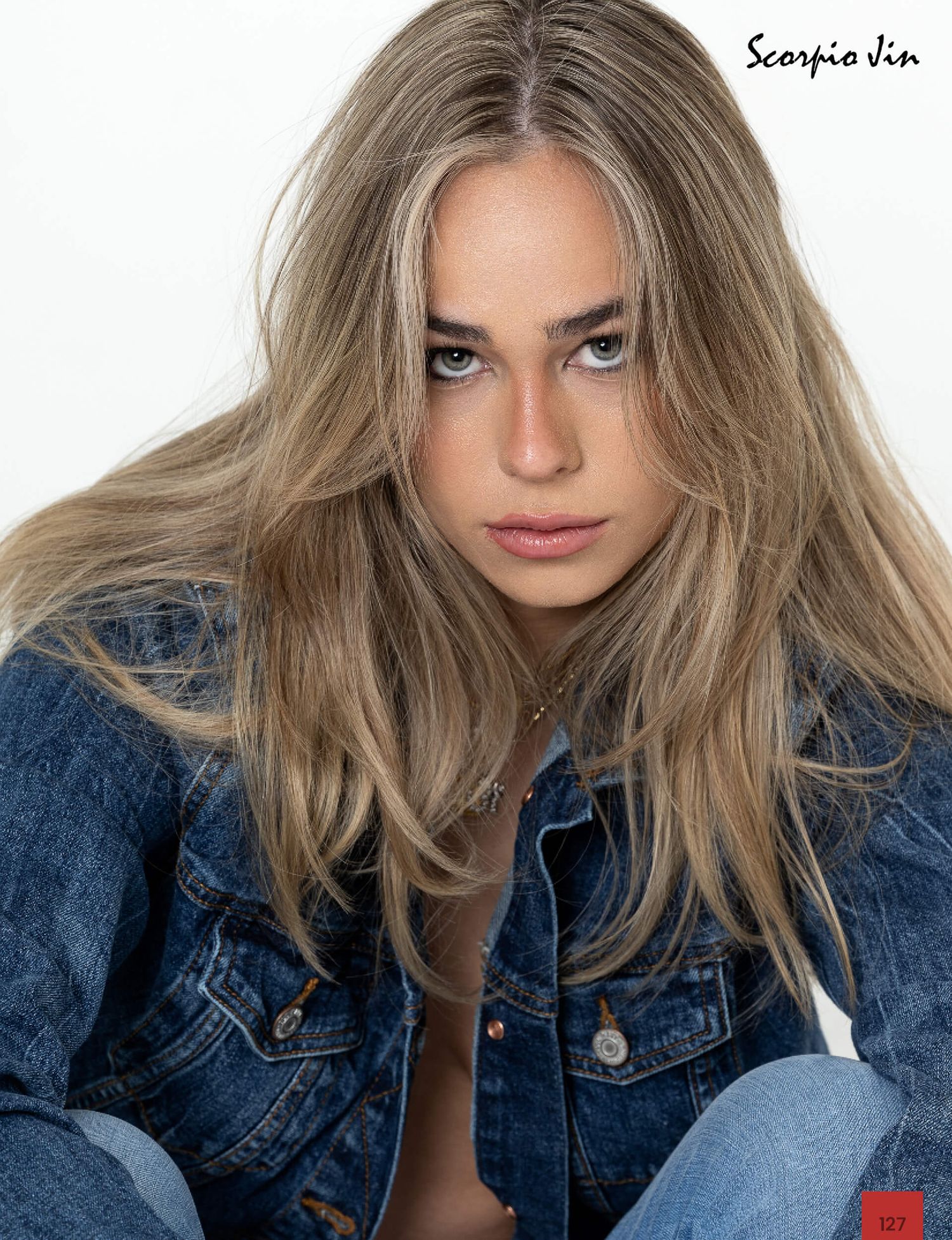 Young blonde model with tousled hair wearing denim jacket in close-up portrait for Scorpio Jin editorial.