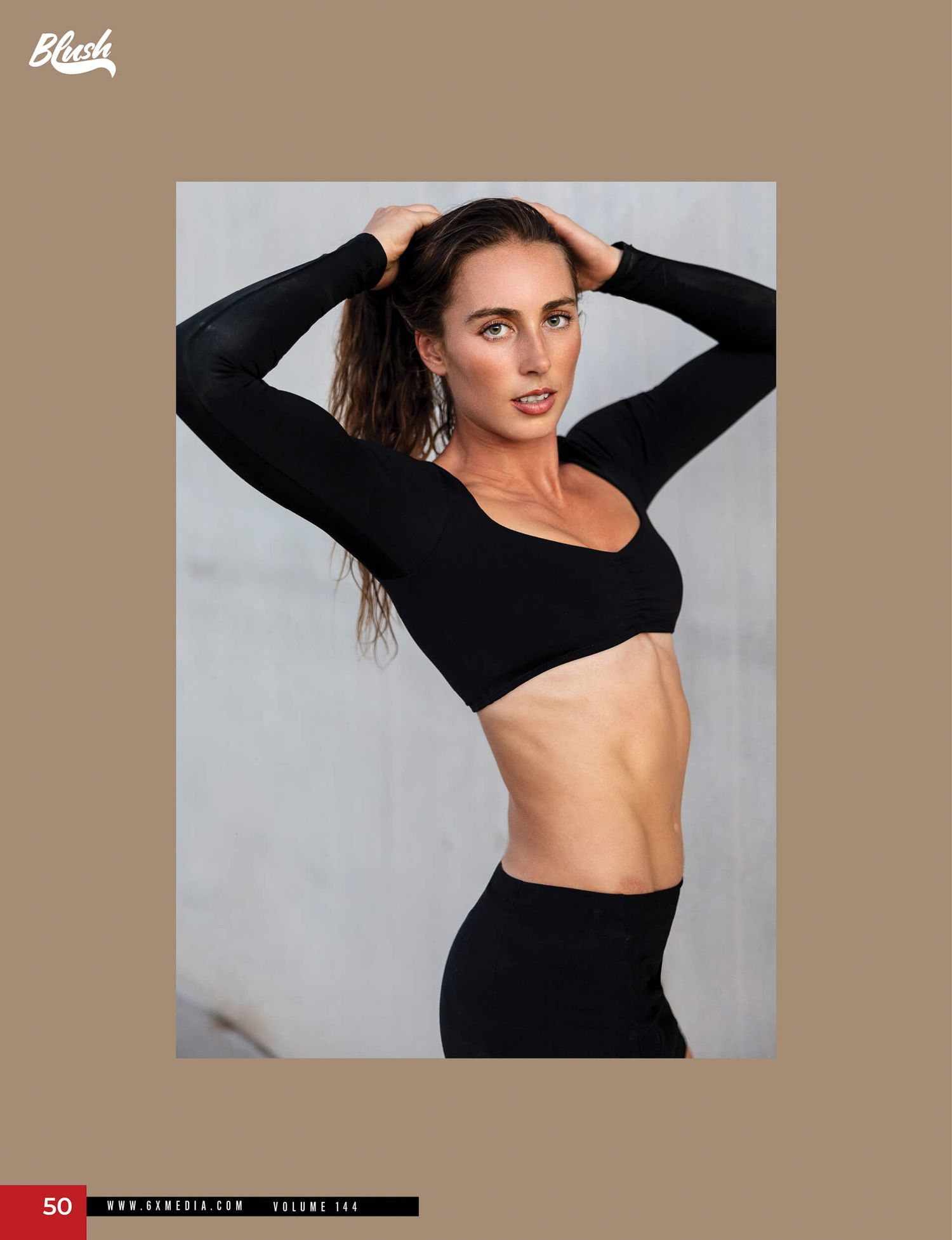 Fit woman in black long-sleeve crop top and leggings posing with hands behind head.